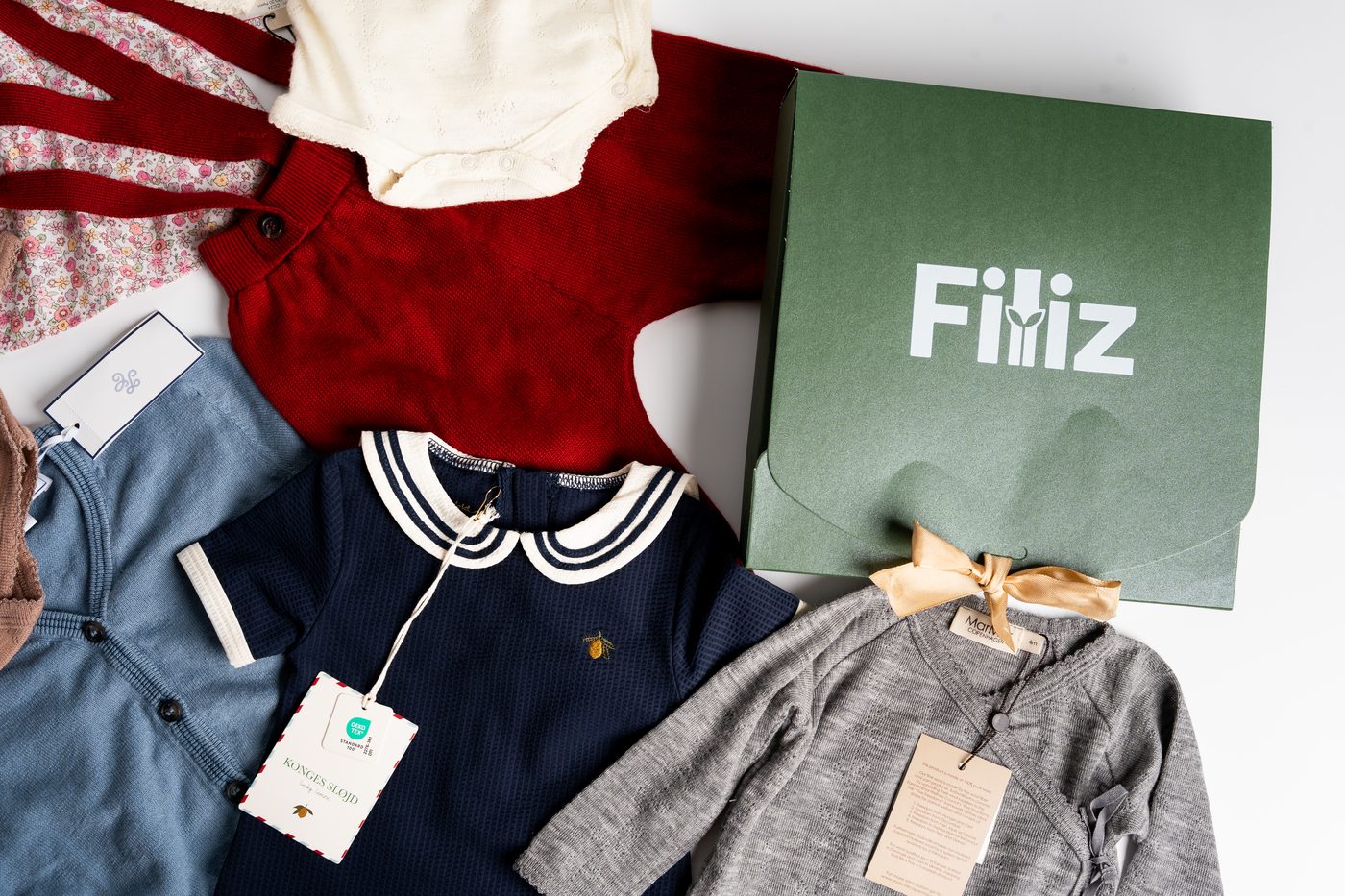 Wide flat-lay of organic baby clothes with Filiz brand tag and box